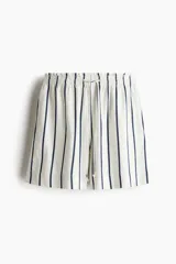 Short de tiro alto con cintura elástica fruncida, cordón de ajuste con cuentas metálicas y bolsillos laterales. Diseño a rayas verticales en color azul marino y blanco.