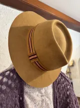 Sombrero de lana color canela con cinta decorativa alrededor de la copa.