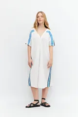 Túnica oversized blanca con bordados en los laterales, botones frontales y apertura lateral.