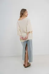 Sweater color crudo de tejido liviano con textura semi traslúcida, escote redondo y mangas amplias estilo murciélago.