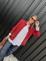 Campera tejida con textura vanizada a rayas horizontales en blanco y negro, con cierre frontal y flecos negros en forma de V en el pecho.