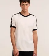 Remera blanca de algodón con cuello redondo y manga corta. Presenta doble raya negra en los hombros y terminaciones en color negro.