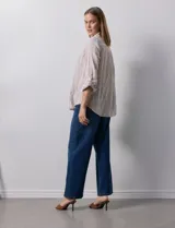 Camisa color beige con rayas verticales blancas, de lino, con cuello con solapa y abertura central con botones. Tiene un bolsillo aplicado en el pecho y mangas largas regulables con presilla y botón.