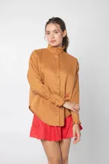 Camisa marrón de lino con cuello mao con volados, manga larga, cierre frontal con botones y bolsillo pequeño en el pecho.