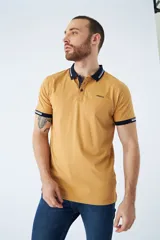 Remera tipo polo color ocre, de corte clásico, con cuello y mangas con terminaciones a contratono en azul marino y blanco.