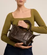 Cartera mini satchel con asa larga ajustable, confeccionada en material sintético PU, con cierre de cremallera y efecto desteñido.