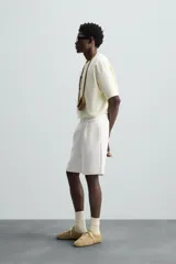 Bermuda color arena de tejido interlock de algodón con elasticidad, corte relaxed fit, cintura elástica ajustable con cordón interior, bolsillos laterales y bolsillo trasero de plastrón.