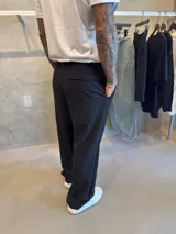 Pantalón de vestir negro, corte sastrero holgado (oversize) con pinzas frontales y cierre de cremallera.