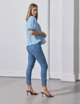 Blusa celeste de gasa marca Zac & Rachel, con cuello redondo, frunces en el frente, mangas 3/4 con puño, abertura central en la espalda y botón.