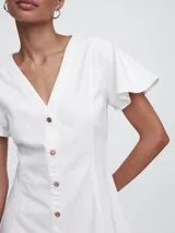 Vestido corto de denim blanco, corte fit and flare, con cuello en V, mangas cortas con volados y cierre frontal con botones.