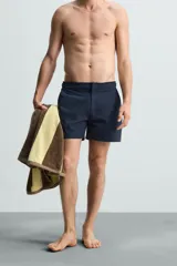 Short de baño celeste de tejido técnico con cintura elástica ajustable con cordón interior y trabillas laterales. Tiene bolsillos frontales y bolsillo trasero con cierre de cremallera. Cuenta con forro interior y cierre frontal con cremallera y botón a presión oculto.