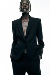 Blazer color beige de corte clásico, con cuello solapa, manga larga, bolsillos frontales con solapa y cierre frontal con un botón.