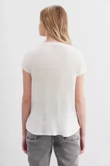 Remera de mangas cortas color crudo, confeccionada en lino y viscosa. Presenta bordados a tono con apliques de lentejuelas, canutillos y mostacillas en la parte superior.