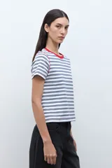 Remera de manga corta con rayas horizontales blancas y azul marino. Presenta cuello redondo con ribete rojo y costuras expuestas en rojo en los hombros.