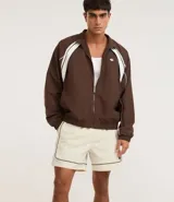 Bermuda deportiva masculina color marrón, con cintura elástica y cordón ajustable. Presenta piping contrastante en blanco a lo largo de los bordes y bolsillos funcionales. Confeccionada en poliamida de secado rápido.