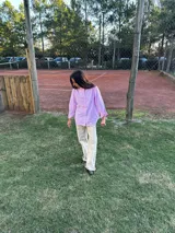 Camisa a rayas verticales rosas y blancas con cuello con volados y mangas largas.
