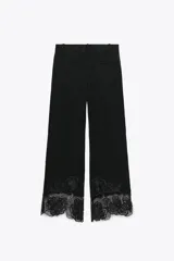 Pantalón culotte negro de tiro alto con pinzas delanteras, bolsillos frontales y falsos bolsillos de vivo en la espalda. Presenta pernera ancha y corta con bordados florales a tono en el ruedo. Cierre frontal con cremallera, botón interior y gancho.