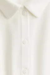 Vestido corto blanco de piqué con cuello polo, tapeta de botones y falda acampanada.