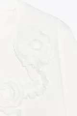 Camiseta blanca de algodón de manga corta y cuello redondo con detalle de flores en relieve en el frente.