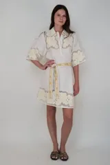 Vestido corto color blanco, confeccionado en lino con detalle de flores aplicadas en el ruedo, mangas y cuello. Incluye lazo a tono para ajustar en la cintura.