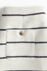 Short de tiro alto en tejido bouclé color crudo con rayas horizontales negras. Presenta pliegues delanteros y traseros, cierre lateral oculto, pinzas traseras, bolsillos al bies y bolsillos traseros de parche con botón metálico. Forrado.
