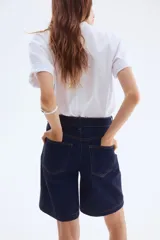 Bermuda de cinco bolsillos en denim de algodón, color azul oscuro. Modelo de tiro alto con cierre y botón metálico.