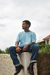 Remera color arena de corte holgado con cuello redondo y mangas cortas. Estampa pequeña en el pecho con la palabra 'Tuya' y un emoji de cara sonriente en color violeta.