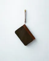 Sobre de cuero color marrón oscuro con correa de mano desmontable.