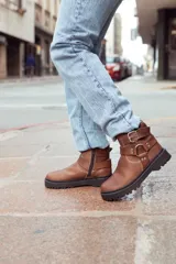 Botas de cuero color marrón con suela track y hebillas decorativas.