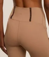 Calza deportiva color café, de microfibra ligera, tiro alto y corte ajustado. Cuenta con elástico en la cintura y tiras porta remera en la espalda.