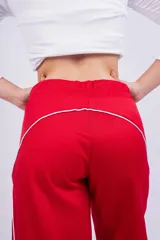 Pantalón deportivo rojo con detalles de líneas blancas curvas en los laterales.