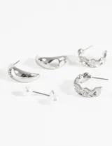 Set de aros plateados que incluye aros con perla, aros en forma de media luna y aros con diseño trenzado.