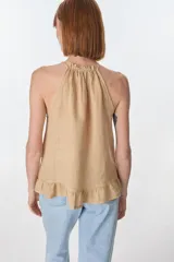 Musculosa color beige de lino, con cuello halter con volados y volados en el ruedo.