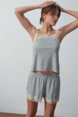 Conjunto de pijama gris compuesto por un top de breteles finos con puntilla en el escote y un short con puntilla en el ruedo.