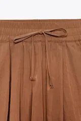 Bermuda color marrón con cintura elástica ajustable con cordones y bolsillos delanteros.
