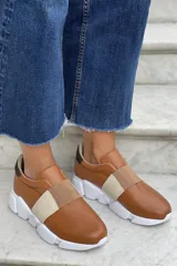 Zapatillas de cuero color beige con detalles en negro, diseño deportivo y suela cómoda.