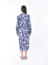Vestido midi camisero con estampado abstracto en tonos celeste y azul marino. Tiene cuello camisero, mangas largas y lazo en la cintura.