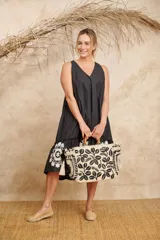 Vestido negro con escote en V, corte holgado, largo midi y volado bordado en el ruedo.