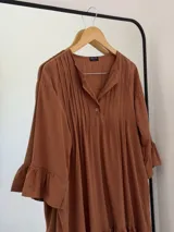 Vestido corto color marrón de fibrana, con cuello mao, tablas en el frente, mangas 3/4 con volados y ruedo con volados.