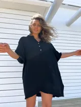 Túnica de playa negra con cuello mao, mangas cortas y ruedo con flecos.