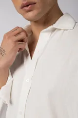 Camisa de manga larga color beige claro, con cuello abierto y calce relajado.