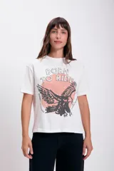 Remera blanca de algodón con cuello redondo y mangas cortas. Estampado frontal con la frase "Born to Ride" y un águila en color negro sobre un círculo rosa.