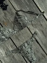 Conjunto de bikini turquesa con corpiño triangular de corte fijo, breteles regulables y almohadillas desmontables, y bombacha vedetina con frunce elástico en los costados.