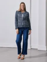 Chaqueta tipo blazer en tejido tweed azul con detalles en blanco y lurex. Tiene escote mao, abertura central, bolsillos delanteros y puños con aplique de botones perlados. Terminación desflecada y forro interno.