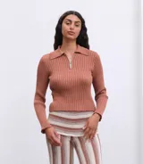 Buzo tejido color burdeos con cierre en el escote y diseño de punto.
