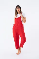 Enterito de lino rojo, tipo jardinera, con tirantes anudados y corte recto que termina a la altura del tobillo. Se lleva sobre una remera blanca de manga corta.