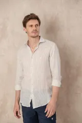 Camisa de manga larga color beige con rayas verticales blancas, confeccionada en lino. Tiene cuello clásico, corte regular y cierre frontal con botones.