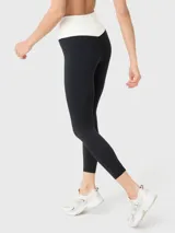 Calza deportiva negra con cintura alta en forma de "V" color crema.