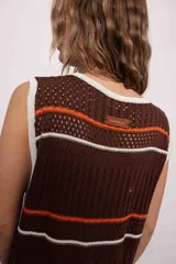 Vestido largo tejido de punto color marrón con rayas horizontales blancas y naranjas, cuello redondo y tajos laterales.