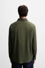 Camisa blanca de corte regular, cuello italiano, manga larga con puños abotonados y cierre frontal con botones.